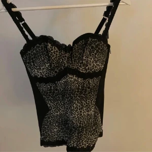 Leopardmönstrad korsettopp - Snygg leopardmönstrad korsettopp med justerbara axelband och spetsdetaljer. Formar midjan  och de svarta gör en bild av en mindre midja och passar mellan XS och M då knäppningen där bak är justerbar!