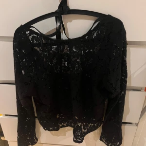 Svart spetsblus från Bik Bok - Snygg svart spetsblus från Bik Bok med långa ärmar och knytband i ryggen. Den är också lite öppet i slutet av ärmarna som gör den mycket snyggare. Köpte den för 299kr och säljer den för 120+frakt 