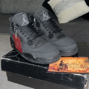 Svarta Nike Air Jordans 4 Retro - Snygga svarta Nike Air Jordans 4 Retro med klassisk design och snörning. Perfekta för sneaker-entusiaster som vill ha en stilren look.