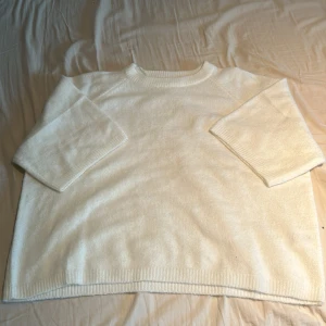 Vit stickad tröja från 157 - Mysig vit stickad tröja från 157 med trekvartsärmar. Perfekt för kyliga dagar och enkel att matcha med olika outfits. Ribbstickade kanter ger en stilren look.