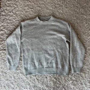 Grå stickad tröja från Solid - Säljer en stilren grå stickad tröja från Solid. Tröjan har en klassisk rund halsringning och långa ärmar med ribbade muddar. Perfekt för kyligare dagar. Xl men passar L bättre