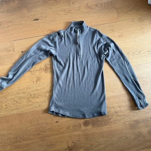 Grå ribbad tröja med dragkedja - Snygg grå ribbad tröja med halv dragkedja och hög krage. Perfekt för kyliga dagar och ger en stilren look. Passar bra till både jeans och chinos.