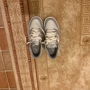 Grå och vita Nike sneakers - Säljer ett par stilrena Nike sneakers i grått och vitt. Skorna har klassisk snörning och en bekväm passform, perfekta för vardagsbruk.