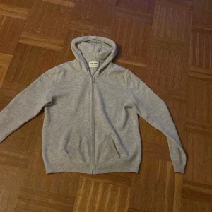 Grå hoodie från Soft Goat - Säljer en mjuk och stilren grå hoodie från Soft Goat i 100% kashmir. Tröjan har dragkedja och långa ärmar, perfekt för kyliga dagar. Den är både bekväm och snygg, ett måste i garderoben! Pris kan diskuteras