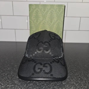 Gucci keps svart - Snygg svart keps från Gucci med det ikoniska GG-mönstret. Perfekt för att ge din outfit en lyxig touch. Justerbar passform för optimal komfort. Billigare vid snabb affär!