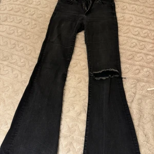 Bootcut jeans med slitningar - Snygga svarta/gråa lågmidjade bootcut jeans med slitningar på ena benet. 