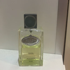 Prada Iris Eau de Parfum - Elegant och sofistikerad doft från Prada. Flaskan är rektangulär med en stilren design och ett silverfärgat lock. Parfymen har en fräsch och blommig doftprofil med inslag av iris och mandarin. Perfekt för den som söker en tidlös och lyxig doft.