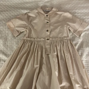 Beige klänning från Zara - Charmig beige klänning från Zara med korta ärmar och knappar framtill. Perfekt för en middag ute på sommaren💕Den är i storlek 140 och är aldrig använd🫶 pris går alltid att diskuteras!