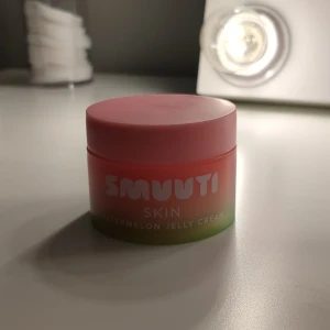 Smuuti Skin Watermelon Jelly Cream - Fräsch och återfuktande ansiktskräm med doft av vattenmelon från Smuuti Skin. Kommer i en söt burk med rosa och grön design. Perfekt för daglig användning för att ge huden en mjuk och len känsla.