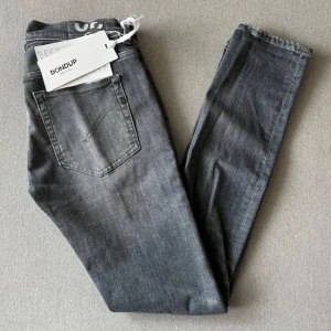 Dondup jeans 30 - Snygga grå jeans från Dondup med en klassisk femficksdesign. De har en knappgylf och bälteshällor, vilket gör dem perfekta för en stilren look. Jeansen har en lätt tvättad effekt som ger dem en modern touch.
