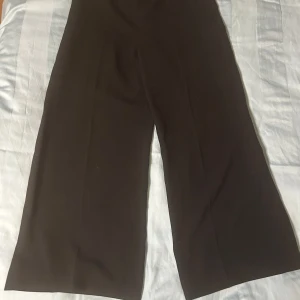 Svarta vida kostymbyxor från Zara Woman - Snygga svarta kostymbyxor från Zara Woman med en vid passform. Perfekta för en stilren look. Tillverkade i Spanien. Det finns en dragkedja på vänster sida så det blir lättare att dra på.