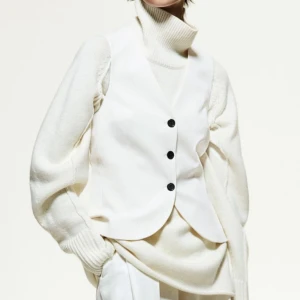Vit väst med knappar - Snygg vit väst med tre svarta knappar framtill. Den har en stilren design och är perfekt för att lägga till en elegant touch till din outfit. Använd och tvättad en gång inga defekter. Storlek 36 Nypris 299 säljer då den inte kommer till användning 
