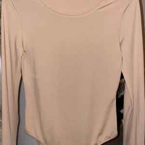 Beige Bodysuit  - Säljer en stilren beige långärmad topp med rund halsringning. Perfekt för lager-på-lager eller som den är. Enkel och mångsidig design.