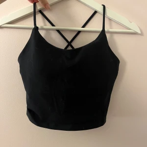 Relode core singlet top - Snygg svart croppad linnetopp från Reload med smala axelband som korsas i ryggen. Obs att de är den äldre varianten av relodes core. Storlek XS