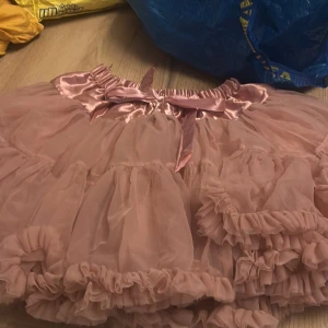 Rosa volangkjol från Buenos Ninos - Söt rosa volangkjol från Buenos Ninos med satinband i midjan. Kjolen har flera lager av volanger som ger en fluffig look. Perfekt för en lekfull stil!