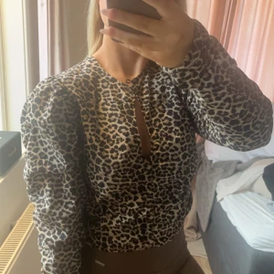 Leopardmönstrad blus med puffärmar - Säljer en trendig leopardmönstrad blus med puffärmar och en liten öppning framtill. Perfekt för att ge din outfit en djärv touch. 🐆