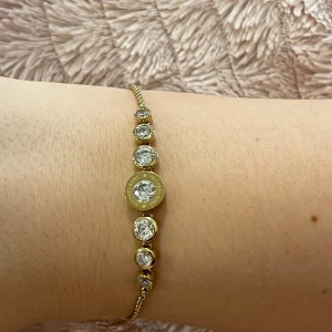 Guldarmband med kristaller - Elegante guldarmband med flera gnistrande kristaller i olika storlekar. Armbandet har en justerbar kedja för perfekt passform och en större kristall i mitten som fångar ljuset vackert.