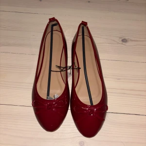 Röda ballerinaskor med rosett - Snygga röda ballerinaskor i lack. Aldrig använda. Köpta i storlek 40 men små i storlek så skulle säga att de passar någon med typ 38/38,5 kanske 39