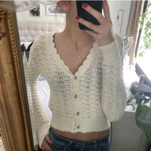 Vit virkad kofta - Säljer en söt vit virkad kofta med knappar framtill. Koftan har långa ärmar och en croppad passform, perfekt till sommaren och våren. Väldigt nytt skick priset kan diskuteras💕