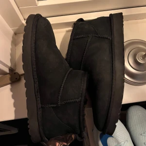 Uggs - Säljer ett par svarta boots från UGG i mocka. De har en klassisk design med rund tå och en bekväm passform. Perfekta för kyligare väder. Storlek 44 