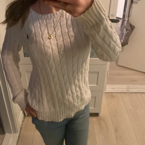 Vit stickad tröja från Ralph Lauren - Säljer en stilren vit stickad tröja från Ralph Lauren med kabelstickat mönster. Tröjan har långa ärmar och en liten broderad logga på bröstet. i storlek XS, kontakta mig innan ni tänker köpa❤️