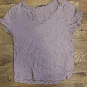 Ljuslila/ rosa  v-ringad t-shirt - Säljer en typ rosa t-shirt med v-ringning. Perfekt för en avslappnad stil. T-shirten har korta ärmar och är tillverkad i ett mjukt material.