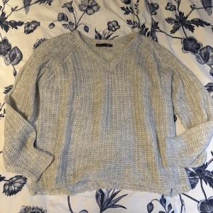 Beige stickad tröja med v-ringning - Mysig beige stickad tröja med v-ringning och långa ärmar. Perfekt för kyligare dagar och ger en avslappnad stil. Tröjan har en mjuk och bekväm känsla.