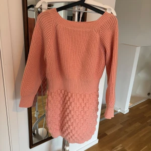 Rosa stickad klänning - Säljer en söt rosa stickad klänning med långärmad design. Klänningen har en unik textur med ribbad överdel och en bubbelliknande struktur på kjolen. Perfekt för kyligare dagar och ger en mysig känsla. Helt ny endast upptvättad. Lappen är bortklippt så har dessvärre ingen ann g vilket märke det var 
