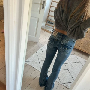 True religion W:24 - JOEY LOW RISE BIG T FLARE JEANS Kostar 1500kr nya. Snygga blå jeans från True Religion med coola broderade detaljer på bakfickorna. W:24