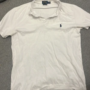 Vit pikétröja från Ralph Lauren - Säljer en klassisk vit pikétröja från Ralph Lauren i modellen Custom Slim Fit. Tröjan har korta ärmar och en broderad logotyp i blått på bröstet. Perfekt för en stilren och avslappnad look.