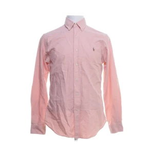 Rosa skjorta från Ralph Lauren - Snygg rosa skjorta från Ralph Lauren i slim fit. Skjortan har långa ärmar och knappar framtill. Perfekt för en stilren look.
