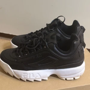 Svarta sneakers från Fila - Snygga svarta sneakers från Fila med vit sula och snörning. Perfekta för en sportig look.