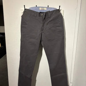 Grå chinos från Morris - Snygga grå chinos från Morris i en klassisk design. Byxorna har en normal passform och är tillverkade av tre-lagers garn för extra hållbarhet. Perfekta för en stilren look. 29/33