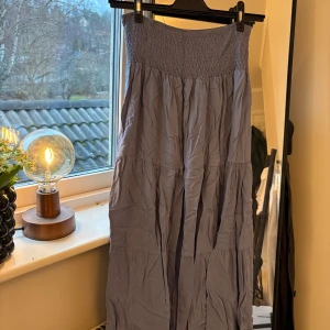 Blå långkjol - Säljer en superfin blå långkjol med smockdetaljer i midjan. Kjolen har en luftig och bekväm passform. Den är i bra skick! Finns ingen storlek men passar för folk som är ca 165cm🌸