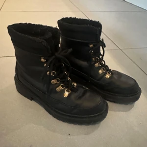 Anna Fiels Svarta boots med snörning - Säljer ett par svarta boots i mycket bra skick. De har snörning och är perfekta för höst och vinter. Bootsens insida verkar vara fodrad för extra värme. De har en robust sula som ger bra grepp.