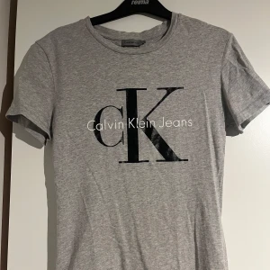  Calvin Klein T-shirt  - Grå t-shirt från Calvin Klein Jeans. Storlek s lite figursydd i fint skick endast använd fåtal gånger 