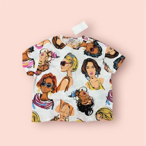 Vit t-shirt med färgglatt ansiktsmönster - Snygg vit t-shirt med ett färgglatt mönster av olika ansikten. Perfekt för en unik och konstnärlig stil. Kortärmad och bekväm passform.