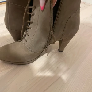 Beige boots med klack och snörning - Snygga beige boots med klack och snörning. De har en dragkedja på sidan för enkel på- och avtagning. Perfekta för en stilren look.