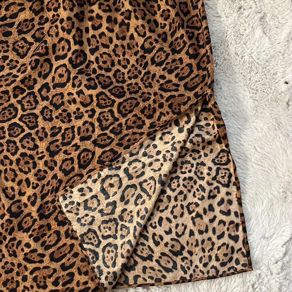 Säljer en supercool leopardmönstrad kjol i brunt och svart. Kjolen är i ett mjukt och glansigt material, perfekt för att sticka ut på festen eller bara för en vardagslook med attityd. Den har en elastisk midja för extra komfort. Passar perfekt till både sneakers och klackar! Men slits på båda sidorna.. Hameet.