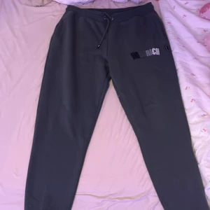 Mörkgråa mjukisbyxor från Hoodrich - Säljer ett par svarta mjukisbyxor från Hoodrich med snörning i midjan och tryck på benet. Perfekta för en avslappnad stil.