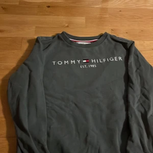 Grå tröja från Tommy Hilfiger - Säljer en stilren grön tröja från Tommy Hilfiger med logga på bröstet. Stl 152 bra skick