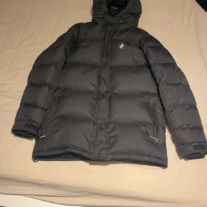 Svart dunjacka från Cross Sportswear - Säljer en svart dunjacka från Cross Sportswear i mycket bra skick. Jackan har en stilren design med dragkedja och huva, perfekt för kalla vinterdagar. Den är långärmad och har praktiska fickor med dragkedjor. Passar både till vardags och utomhusaktiviteter. Supervarm och bekväm! Storlek Xs men sitter som S/M