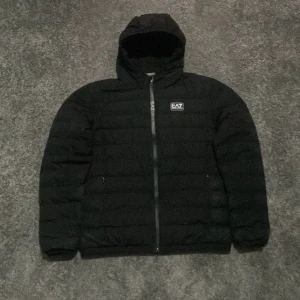 Svart pufferjacka från Emporio Armani - Säljer en svart pufferjacka från Emporio Armani, EA7. Jackan har en stilren design med dragkedja och huva, perfekt för kyliga dagar. Den är i mycket bra skick och passar både till vardags och lite finare tillfällen. Storleken är herr S. Perfekt för höst och vinter! (Accepterar endast Swish pga lurendrejerier) (Checka även in andra schyssta kläder på min profil och köp tillsammans för ett rabatterat pris)  