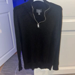 Svart stickad tröja från H&M - Säljer en svart stickad tröja från H&M i storlek M. Den har en dragkedja vid halsen och långa ärmar. Perfekt för höst och vinter, supermysig och stilren. Passar både till vardags och lite finare tillfällen. 🖤