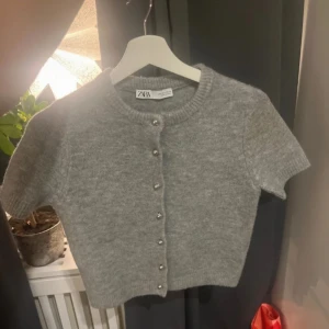 Grå kofta från Zara - Säljer en superfin grå kofta från Zara. Den är kortärmad och har snygga knappar framtill. Perfekt för både vår och höst! Koftan är i bra skick och passar till många olika outfits. Perfekt för att lägga till en touch av stil till din garderob. 🩶
