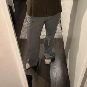 Grå kostymbyxor - Snygga grå kostymbyxor med bootcut-stil. De har en klassisk design med knappar och dragkedja framtill. Perfekta för en stilren look. Jag är 1,67 som referens 