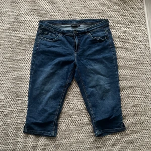 Blå Capribyxor från KappAhl - Säljer ett par blå capribyxor från KappAhl. De har en klassisk design med fem fickor och dragkedja. Perfekta för en avslappnad stil.