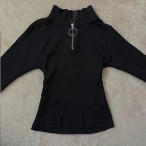 Svart ribbad tröja med dragkedja - Snygg svart ribbad tröja med en dragkedja framtill och stretchig passform. Använd ett par gånger men i god skick. Strl XS