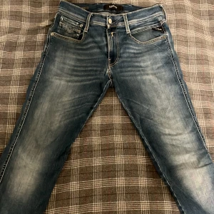 Replay Anbass Jeans - Snygga blå jeans från Replay, modell Anbass. De har tyvärr ett litet hål (bild 4) och därav priset. Storleken är 28/32 men sitter som 30/32