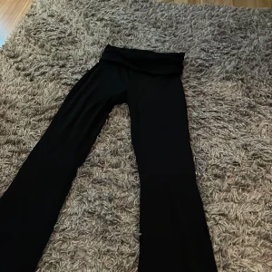 Svarta byxor med utsvängda ben - Snygga svarta byxor med utsvängda ben, perfekta för en trendig look. De har en hög midja och är gjorda i ett mjukt och bekvämt material.